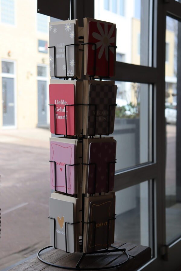 Kaartenmolen gevuld met ansichtkaartjes van Goed Faut in een winkel